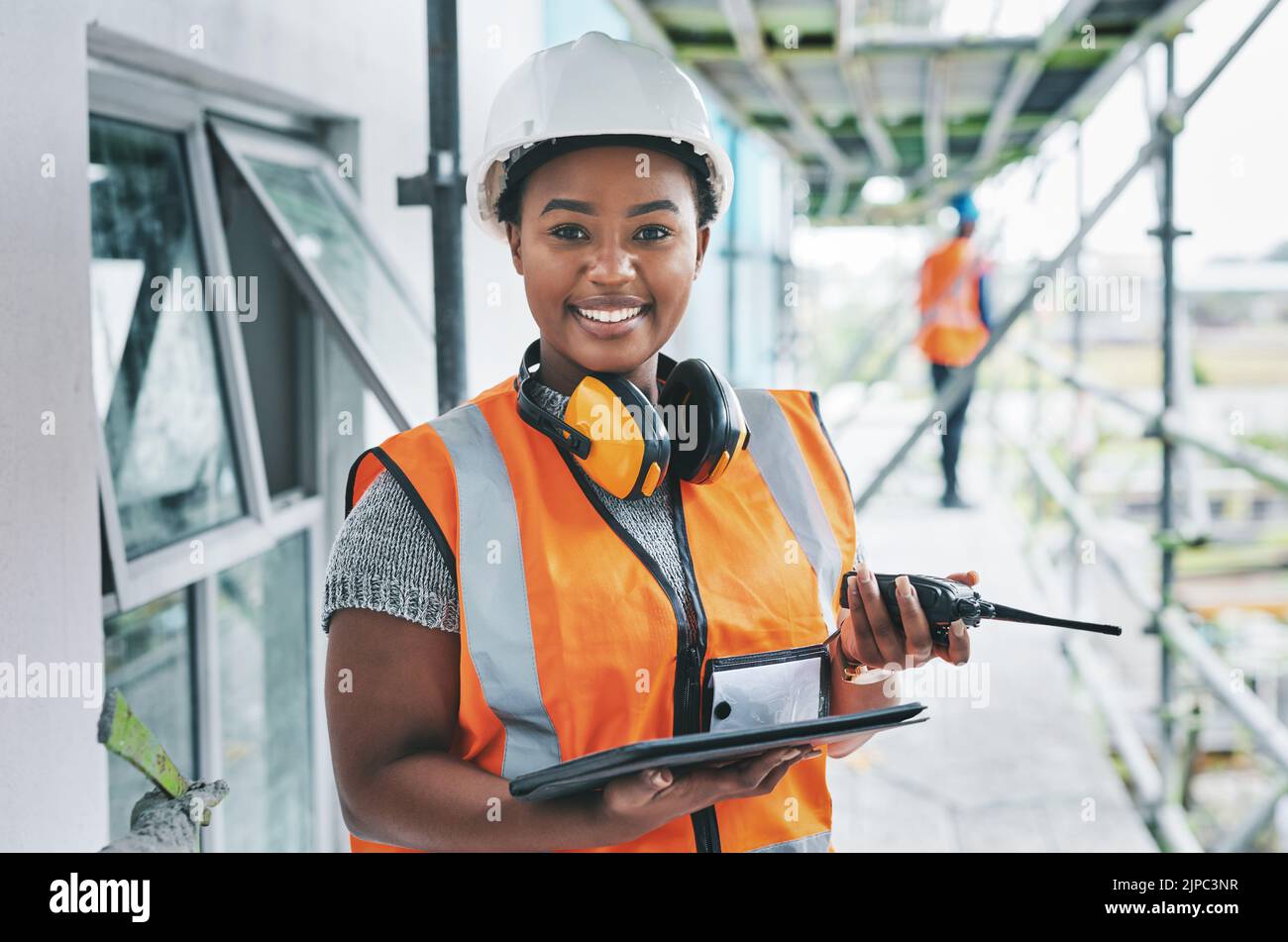 Portrait d'un ouvrier de construction noir fier de diriger avec de la puissance tout en gérant la logistique du site sur une tablette. Une femme ingénieure heureuse supervise un bâtiment Banque D'Images