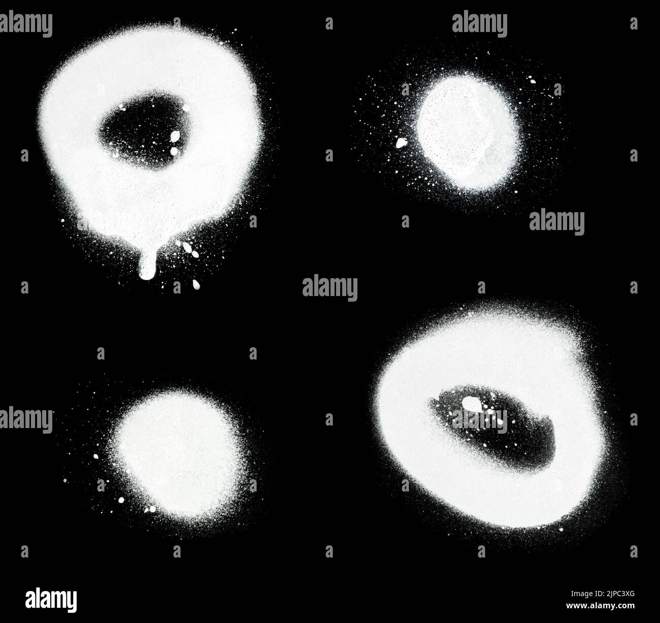 Gros plan de deux taches de peinture en aérosol blanc et de cercles avec éclaboussures et gouttes, isolés sur fond noir. Banque D'Images