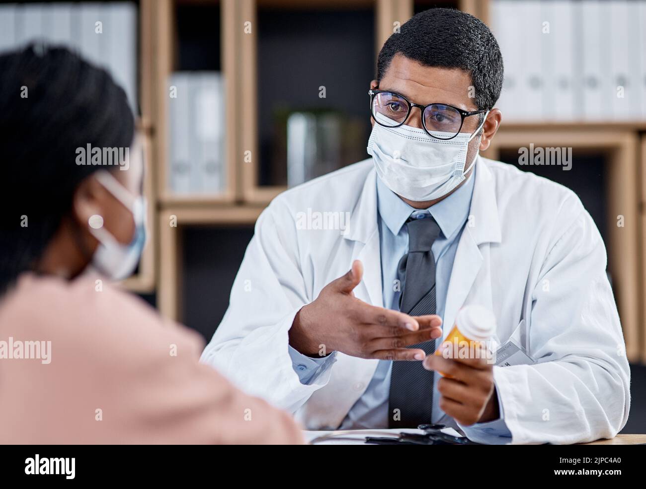 Rendez-vous médical ou médecin consultant un patient pendant la pandémie de covid depuis son bureau. GP masculine aidant un client malade en lui donnant des comprimés Banque D'Images