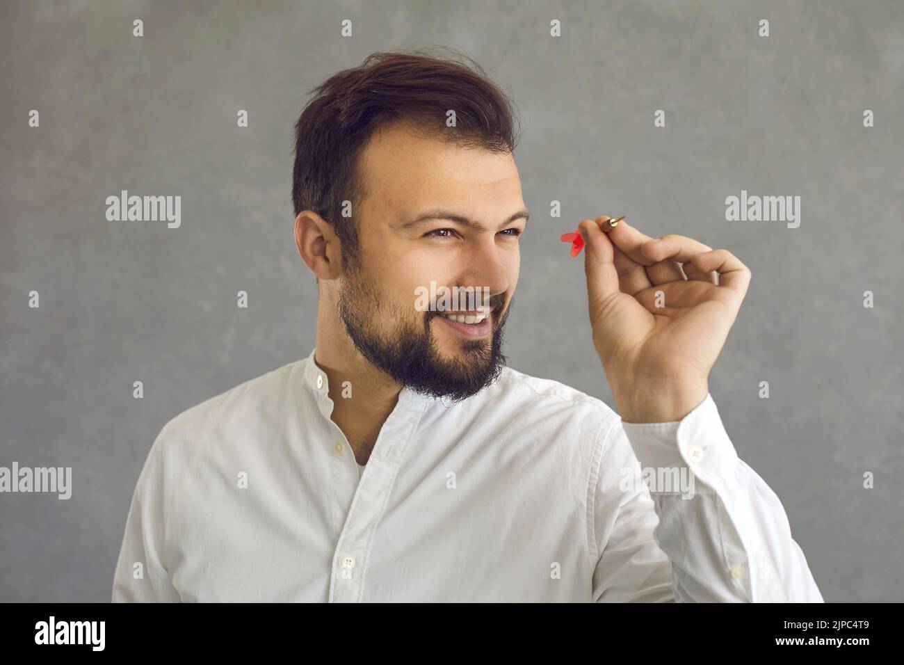 Portrait d'un jeune homme d'affaires prospère et confiant visant une flèche de fléchettes à une cible Banque D'Images
