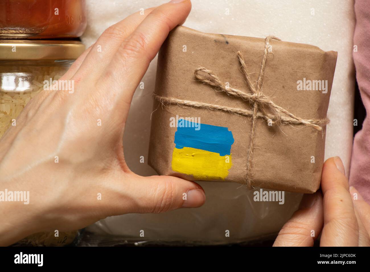 Une boîte avec un drapeau jaune-bleu peint de l'Ukraine dans la main d'une femme, l'aide humanitaire pour l'Ukraine de la part du peuple Banque D'Images