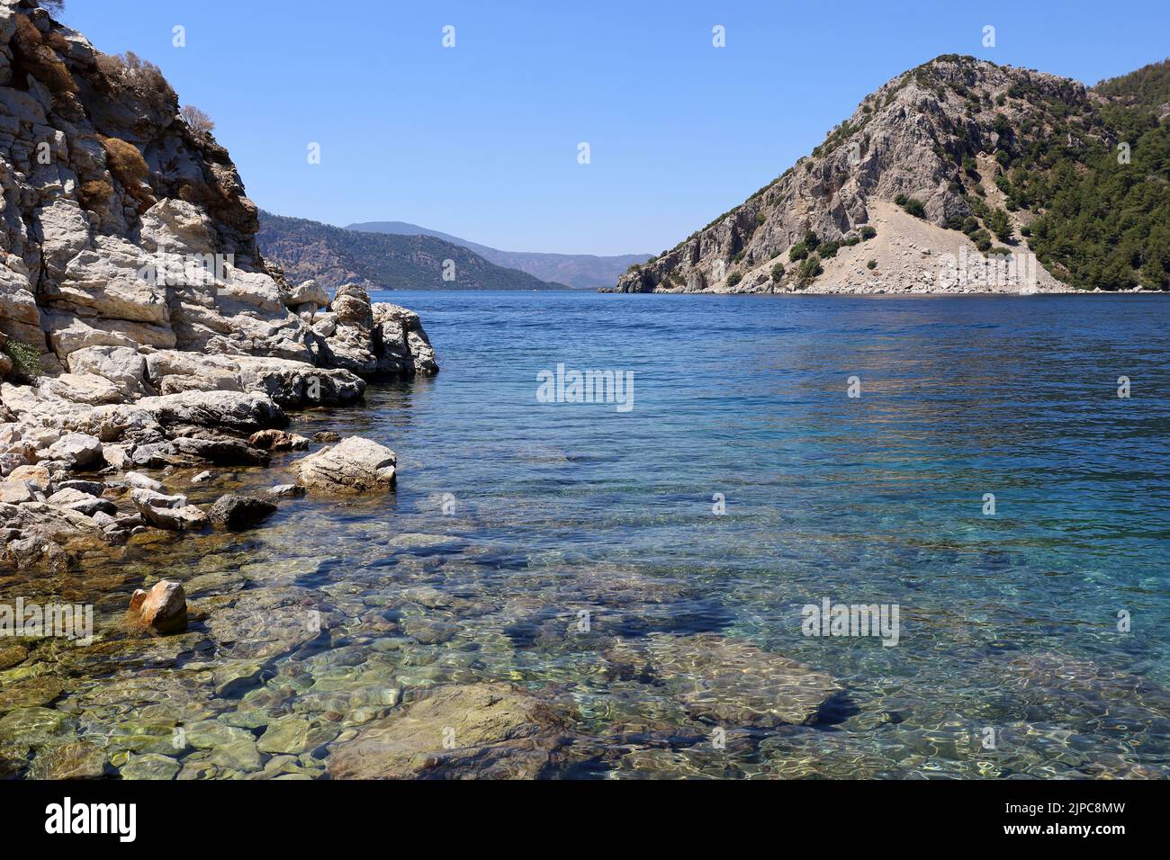 Vue pittoresque sur l'île aux rochers dans la mer Méditerranée. Côte d'été avec eau turquoise transparente, pierres sur un fond et montagnes vertes Banque D'Images