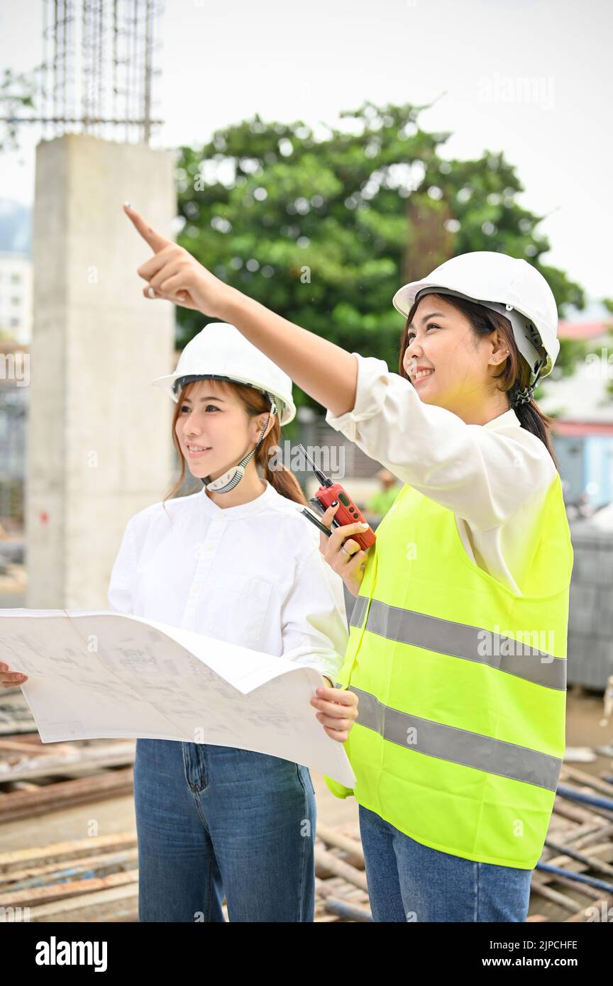 Belle et professionnelle, jeune femme ingénieur asiatique et architecte sont en train de discuter et de planifier le plan de construction à l'emplacement de construction tog Banque D'Images