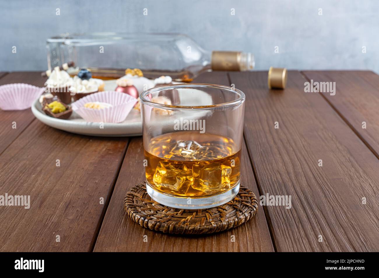 Verre de whisky avec glace. À l'arrière-plan, des bonbons brésiliens sophistiqués pour les mariages. Banque D'Images