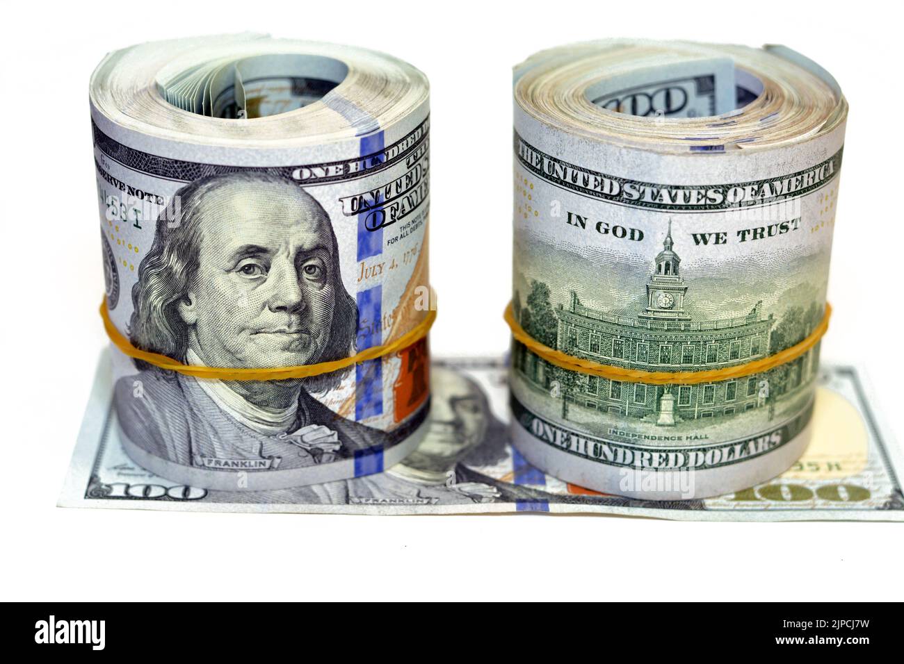 Paquets de rouleaux d'argent de dollars isolés sur fond blanc, pile de cent dollars US cash billets roulés avec des bandes de caoutchouc avec l'esprit Banque D'Images