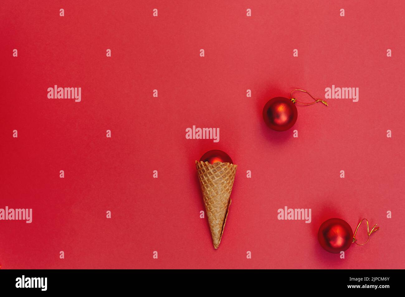 Décoration de Noël dans un cône gaufré sur fond rouge. Jouets ronds avec fil d'or. Autre concept de célébration des vacances d'hiver, vue du dessus composition festive. Pose à plat Banque D'Images