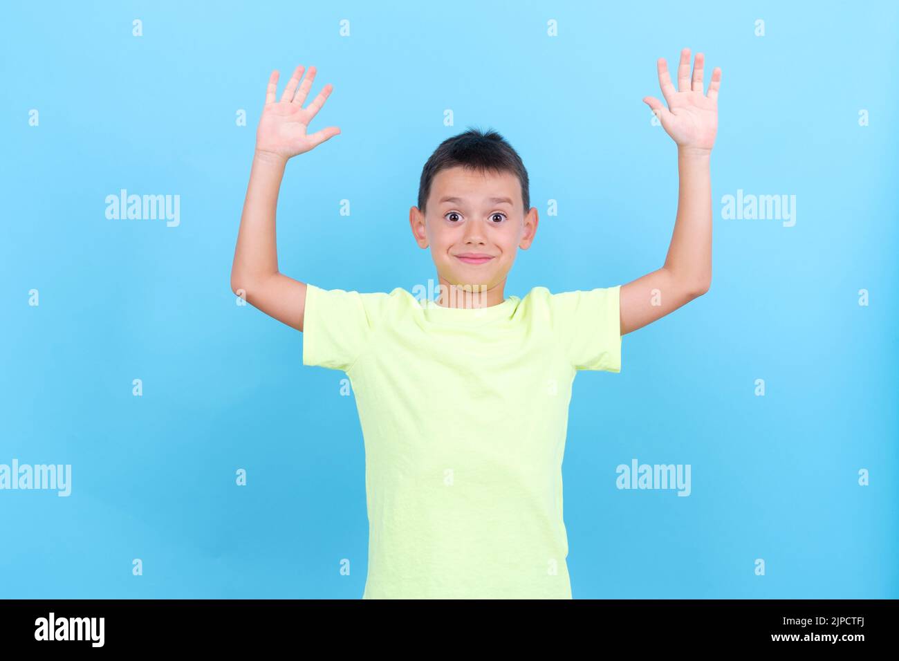 un garçon de 8 ans lève les mains d'un geste surpris Banque D'Images