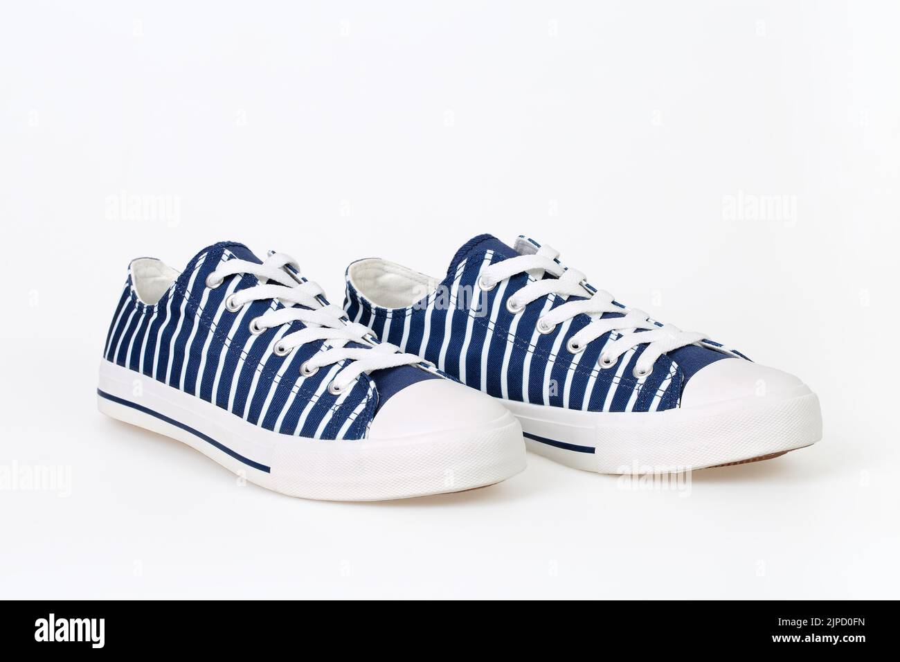 Paire de nouvelles sneakers tendance à rayures bleu marine et blanc sur fond blanc. Banque D'Images