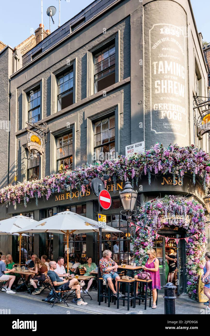 Personnes assises à l'extérieur de la taverne de M. Fogg, à St Martin Lane, Londres, Royaume-Uni. Banque D'Images