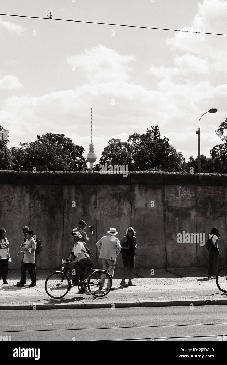 Un cliché vertical de personnes en face de l'ancien mur de Berlin avec la tour de télévision de Berlin en Allemagne Banque D'Images