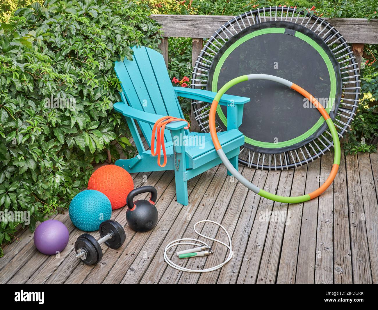 home gym et concept de loisirs - balles de slam, kettlebell de fer, haltères, mini trampoline, bande de résistance, Corde de saut, et hula hoop avec Adirondack ch Banque D'Images