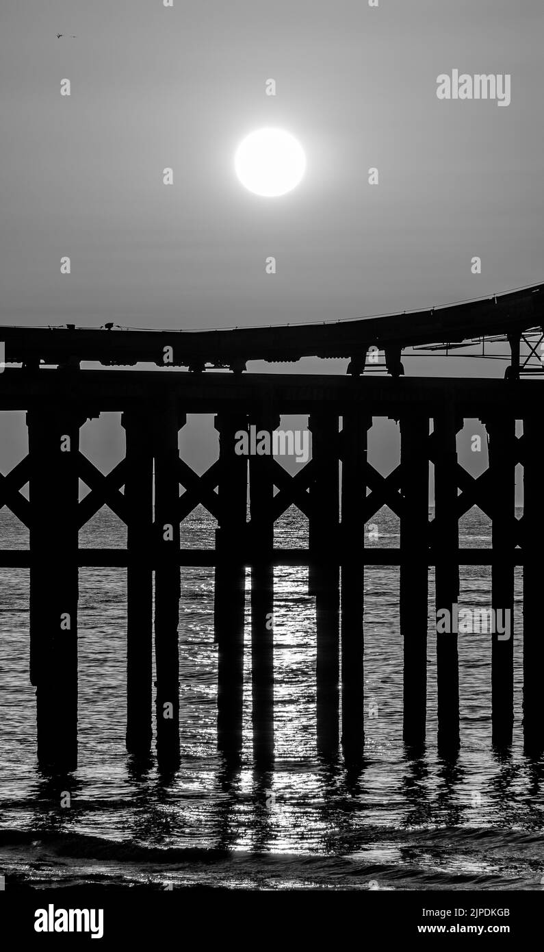 Image monochrome d'un coucher de soleil sur une partie d'une jetée. Banque D'Images