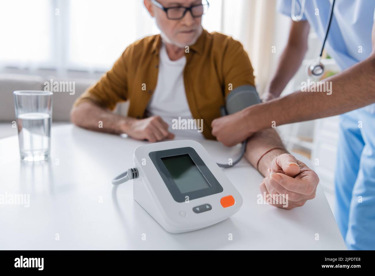 Tonometer près de flou afro-américain infirmière et patient à la maison Banque D'Images
