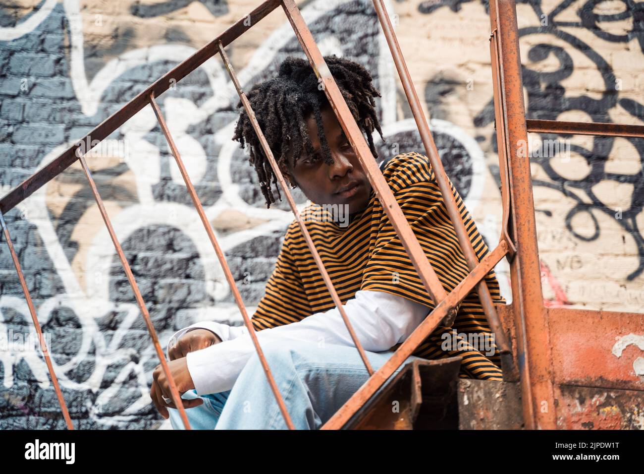 Jeune homme élégant noir avec des dreadlocks de cheveux naturels. Afroamerican Guy.Stairs, mur peint avec des graffitis dans le quartier pauvre de l'art de rue cultur Banque D'Images