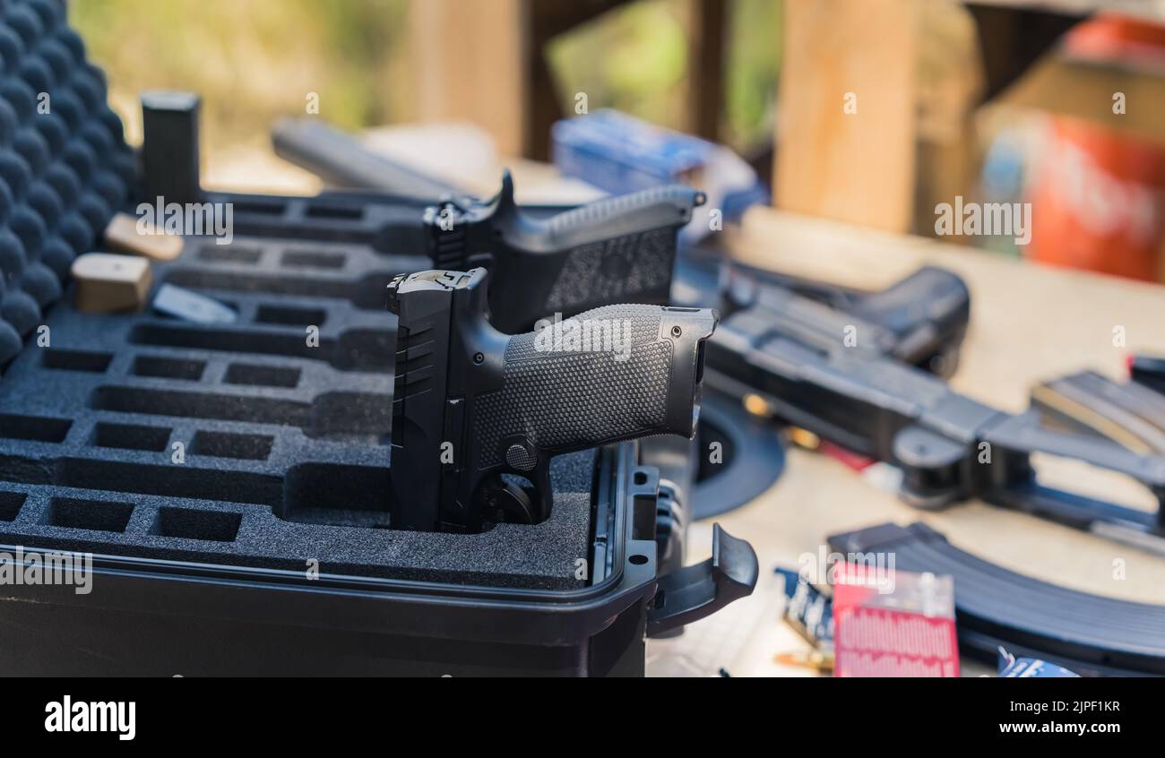 Pistolets stockés dans un coffret métallique sur une table en bois avec des pinces et diverses munitions. Équipement militaire, champ de tir. Mise au point sur le premier plan. Tir horizontal . Photo de haute qualité Banque D'Images