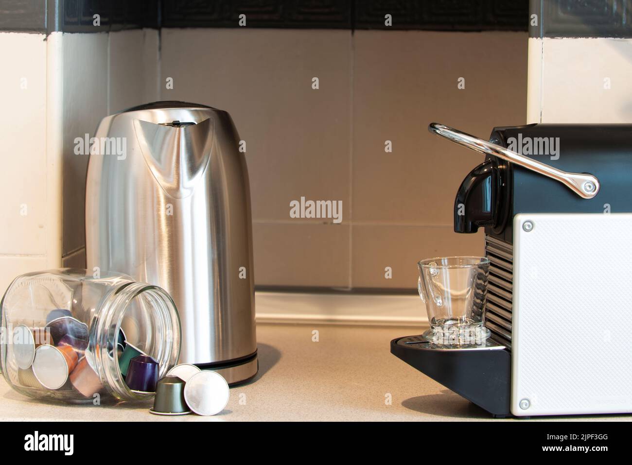 Préparer un latte dans une cuisine avec une machine à café capsule avec un plan de travail gris et des capsules de différentes forces Banque D'Images