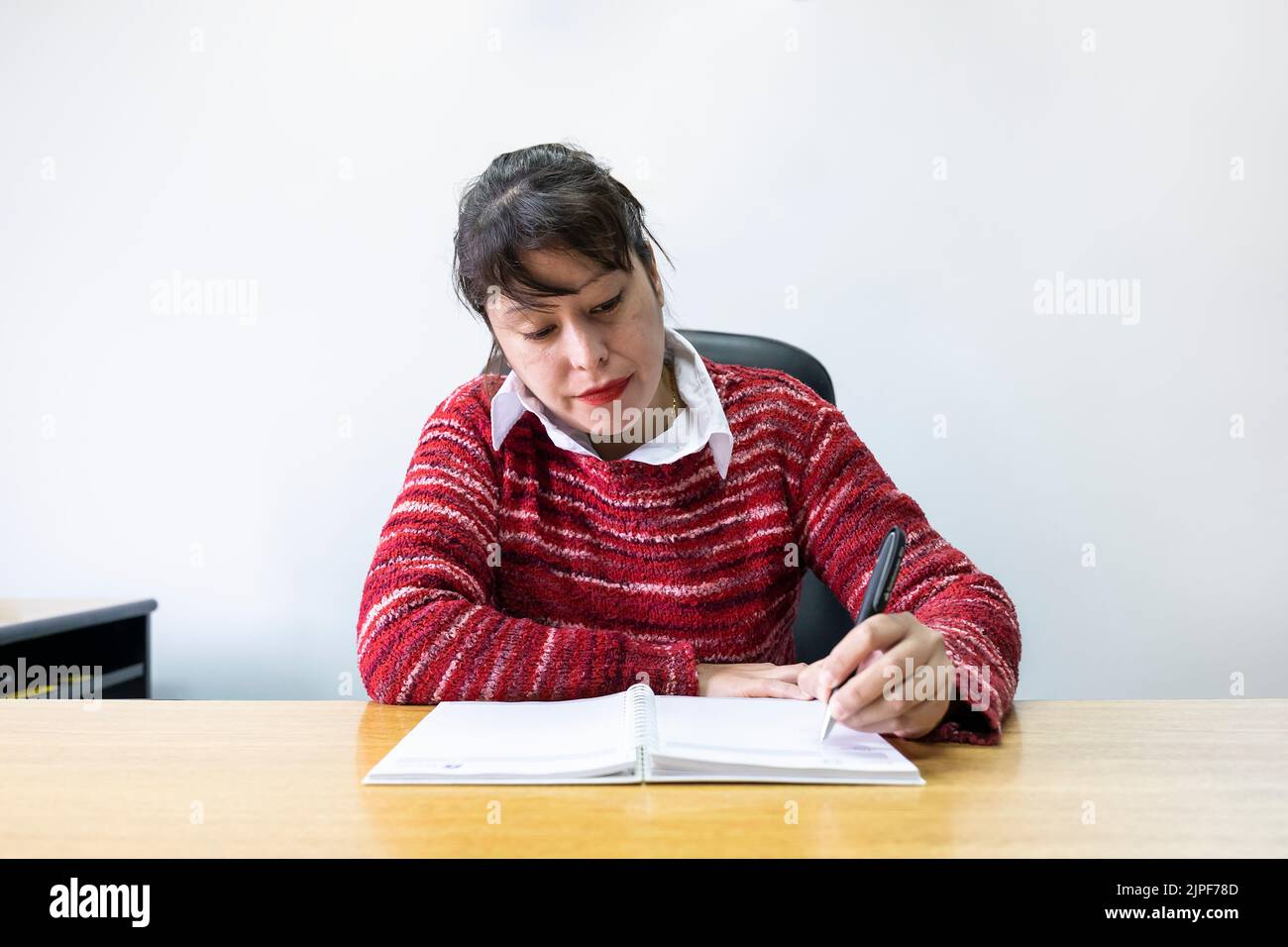 Femme d'affaires latine assise à son bureau pour prendre des notes Banque D'Images