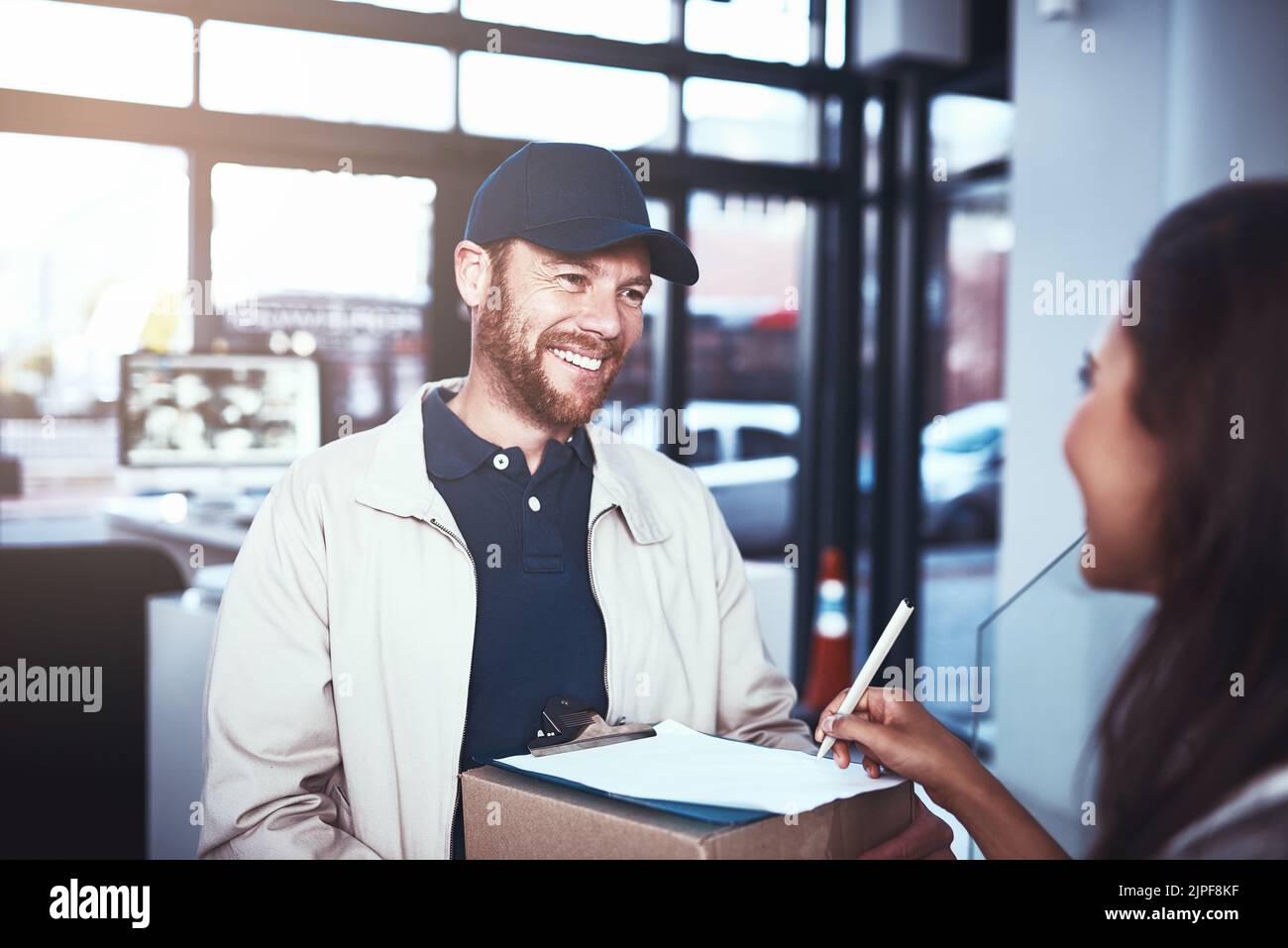 Nos livraisons sont toujours gratuites et rapides. Un liveur joyeux donne un colis à un client et lui laisse signer une tablette numérique à l'intérieur Banque D'Images