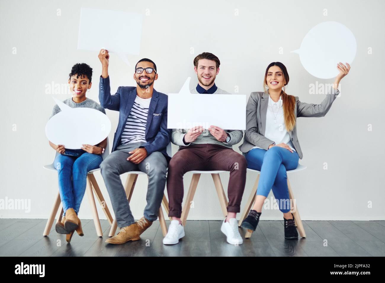Votre opinion compte, ayez votre mot à dire. Un groupe diversifié d'employés créatifs tenant des bulles de parole à l'intérieur. Banque D'Images