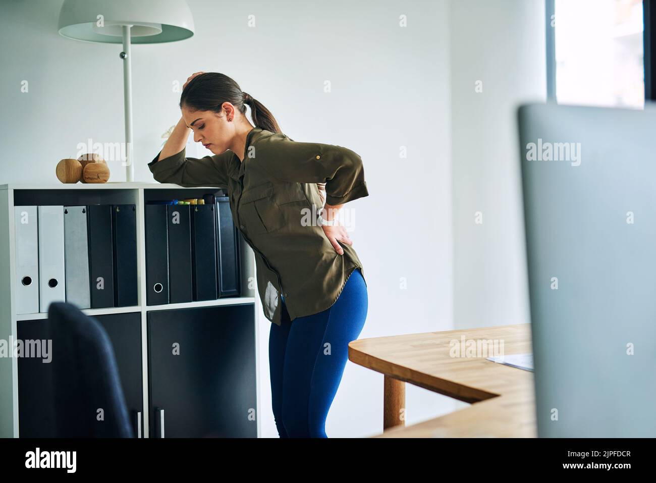 Son dos est lourd de stress : une jeune femme d'affaires souffre de maux de dos dans un bureau. Banque D'Images