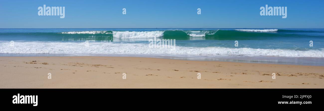 Panorama des vagues de surf se déroulant sur la plage par une journée d'hiver calme et ensoleillée. Banque D'Images