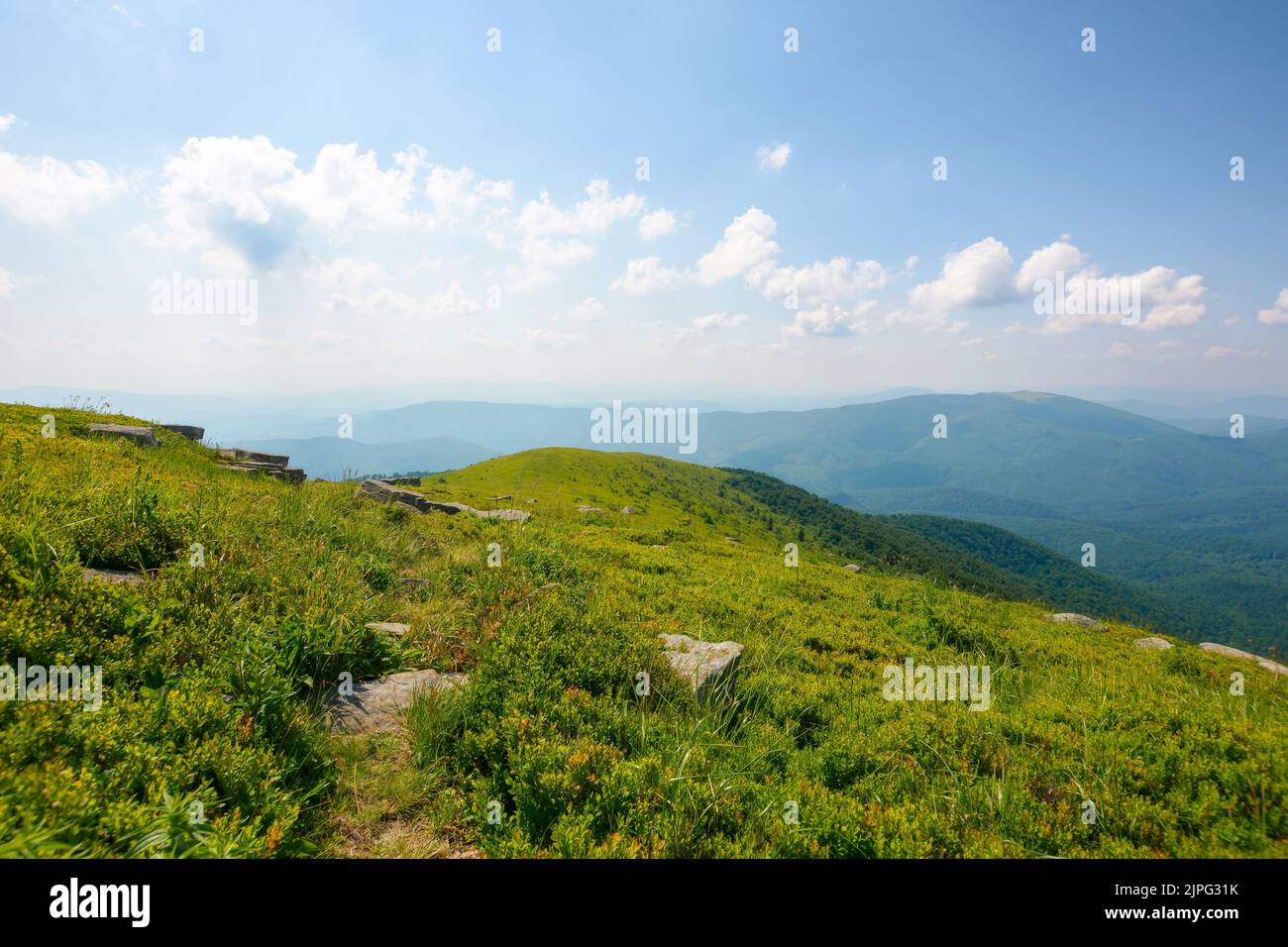 descendez la colline herbeuse. pierres sur la prairie verte à flanc de colline. vacances d'été en montagne. temps ensoleillé l'après-midi avec des nuages moelleux sur le ciel Banque D'Images