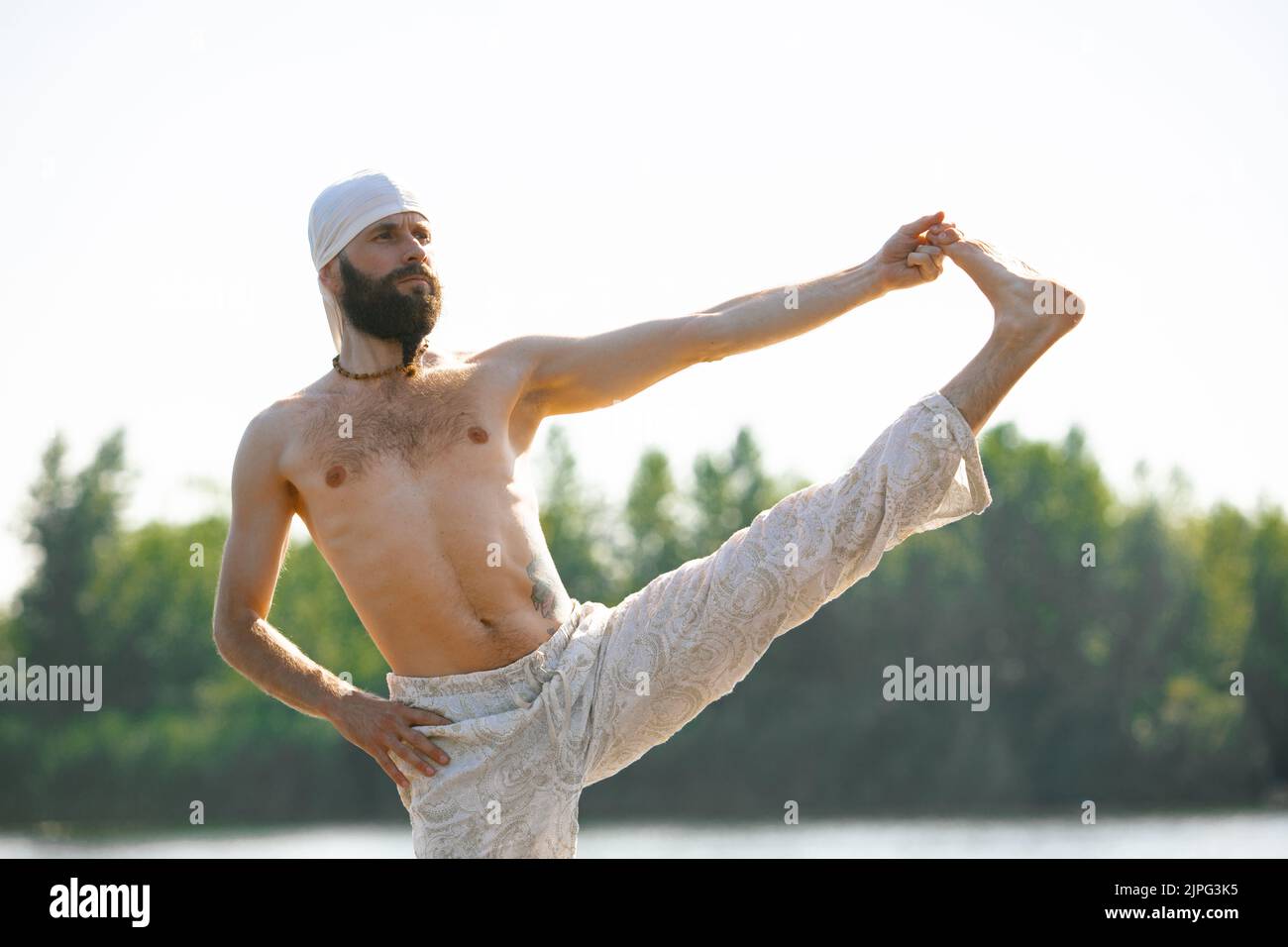 Gros plan jeune homme pratiquant le yoga sur la berge de la rivière au lever du soleil, en plein air. Concept de santé mentale, relaxation, harmonie avec la nature Banque D'Images