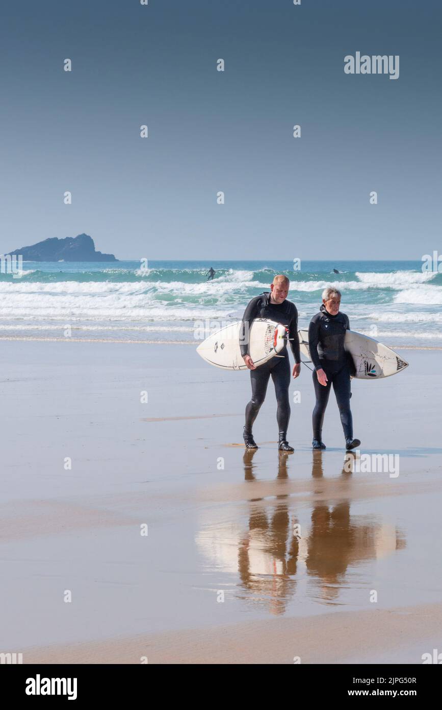 Deux surfeurs matures marchant sur la plage après une séance de surf à Fistral à Newquay, en Cornouailles, au Royaume-Uni. Banque D'Images