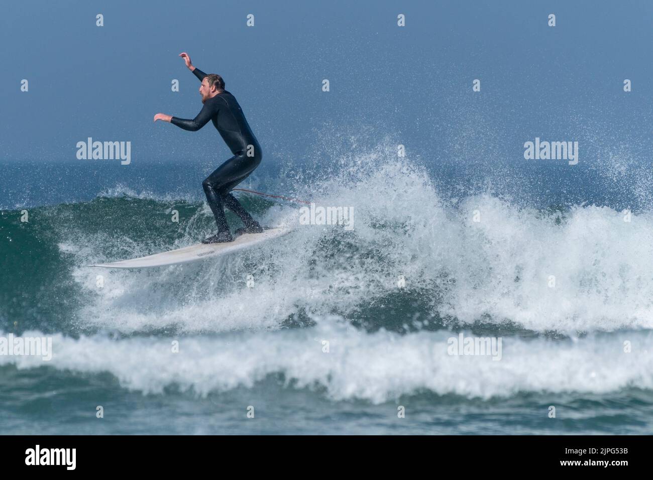 Un surfeur mâle qui fait une vague à Fistral, à Newquay, en Cornouailles, au Royaume-Uni. Banque D'Images