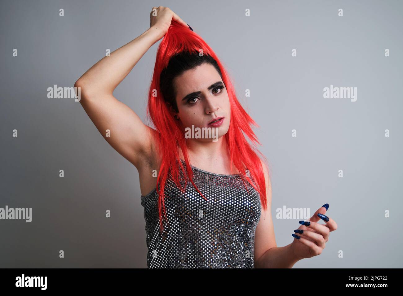 Portrait d'une reine de drag qui déchge la perruque rouge et regarde l'appareil photo. Banque D'Images