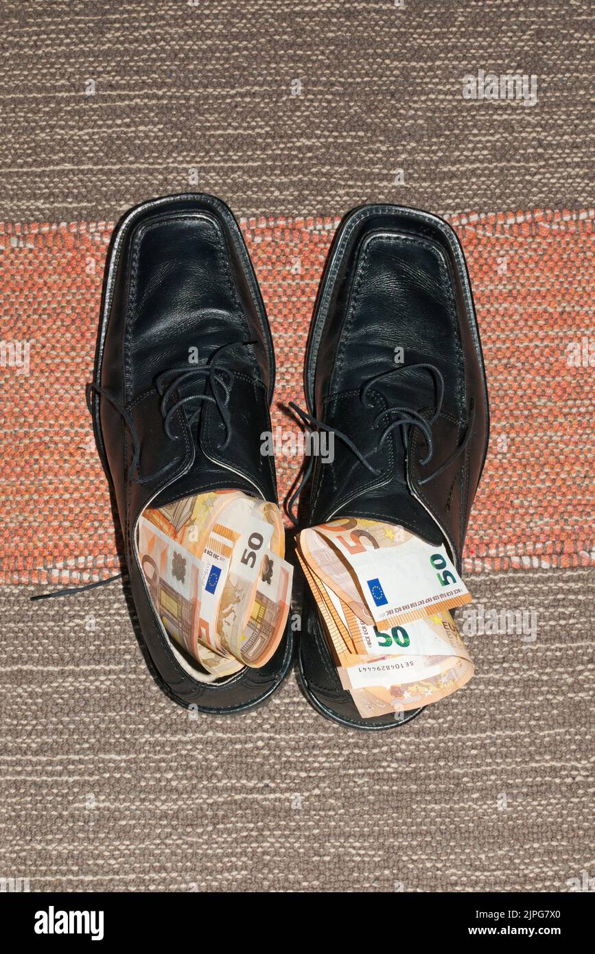 chaussures mâles noires sur tapis farcies de 50 billets en euros Banque D'Images