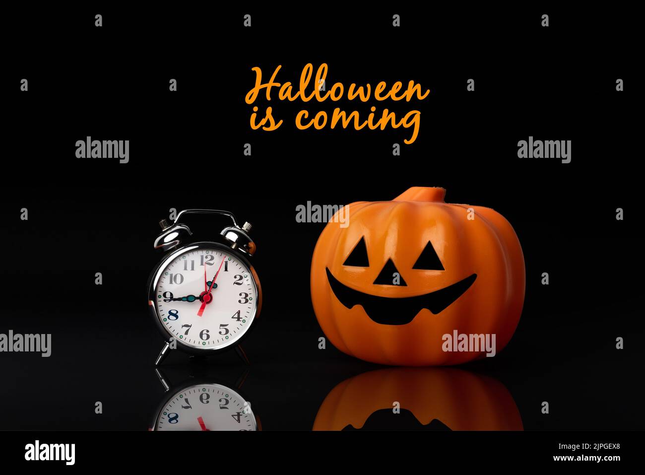 Halloween arrive. Citrouille en peluche à côté d'une horloge symbolisant les fêtes d'Halloween. Il est temps de se déguiser en sorcière ou zombie Banque D'Images