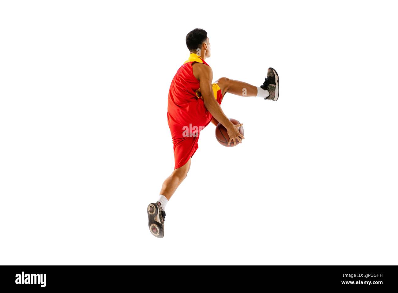 Portrait dynamique d'un jeune homme, joueur de basket-ball qui lance une balle dans un saut isolé sur fond blanc de studio. Dribble Banque D'Images