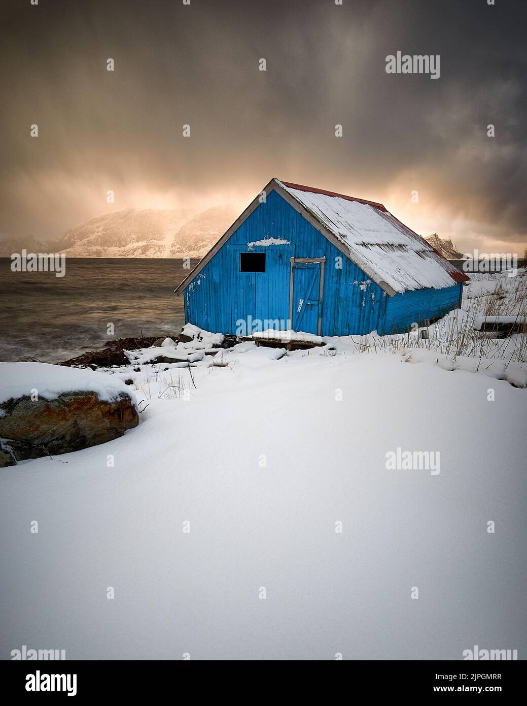 Blue Boat House pendant un blizzard au coucher du soleil, Godøy, Sunnmøre, Møre og Romsdal, Norvège. Banque D'Images