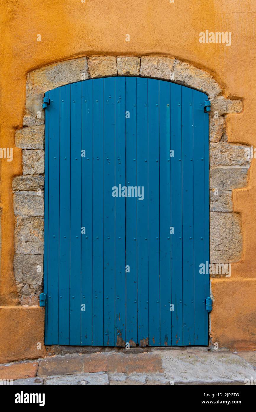 Ancienne porte en bois bleu entourée de pierres coupées, sur une maison à façade ocre dans une rue de la vieille ville d'Hyères, dans le sud de la France Banque D'Images