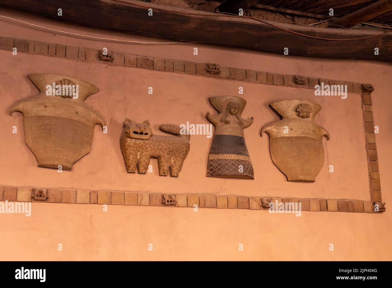 Des figures de céramique de style autochtone préhispanique décorent le mur d'un restaurant à San Pedro de Atacama dans le nord du Chili. Banque D'Images