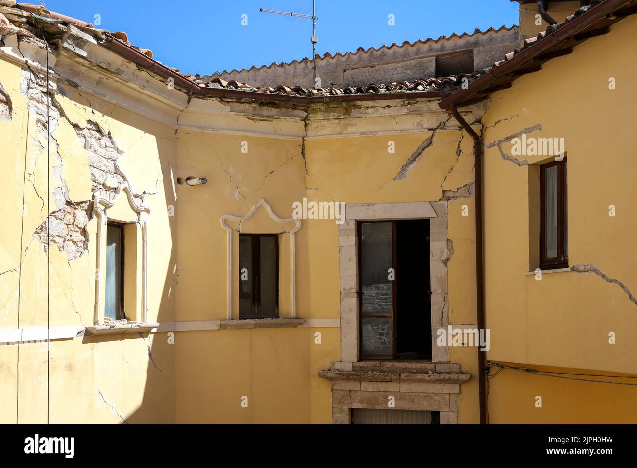Grandes fissures et plâtre ébréché sur les murs d'une maison qui a été frappée par un tremblement de terre dans une ville ombrienne. Banque D'Images
