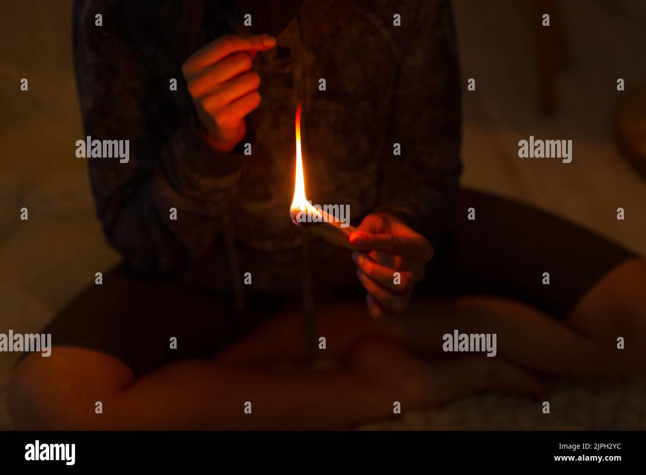 Adulte mature femme faisant du yoga à la maison salon fixe le feu avec l'arbre de bâton de palo santo Banque D'Images