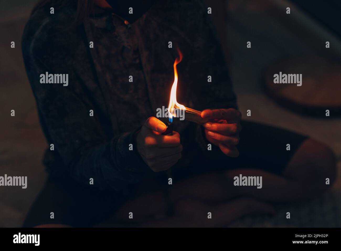 Adulte mature femme faisant du yoga à la maison salon fixe le feu avec l'arbre de bâton de palo santo Banque D'Images