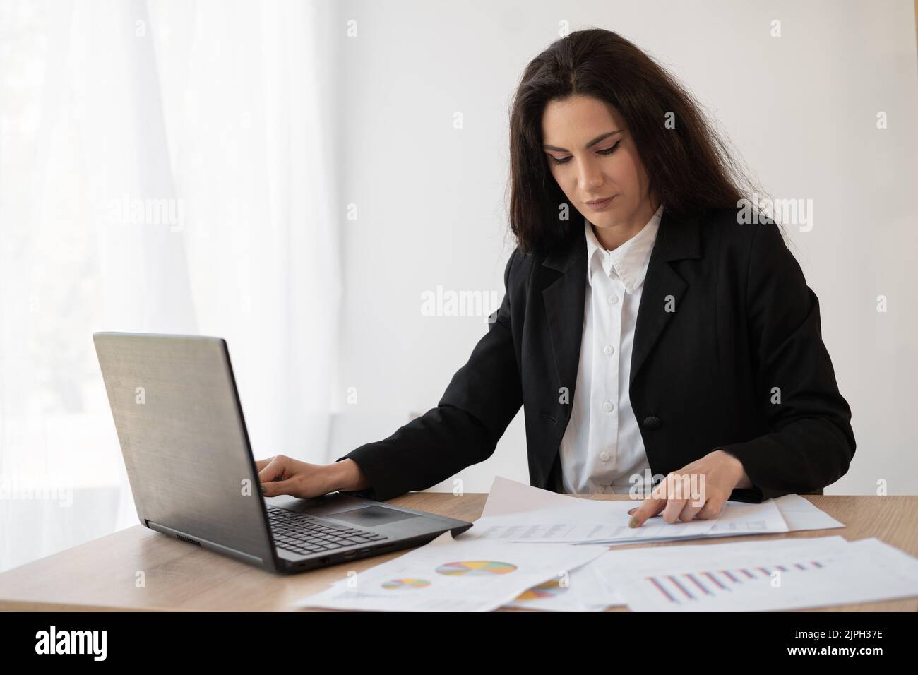 Sérieuse femme d'affaires dactylographie des documents sur un ordinateur portable, la préparation d'un rapport avec l'analyse des résultats de travail, femme entrepreneur fait de la paperasse à Banque D'Images