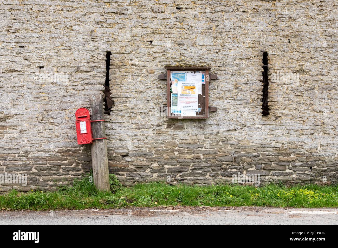 Boîte postale rurale du Royal Mail et panneau d'affichage du village sur le mur de l'ancienne grange en pierre Banque D'Images