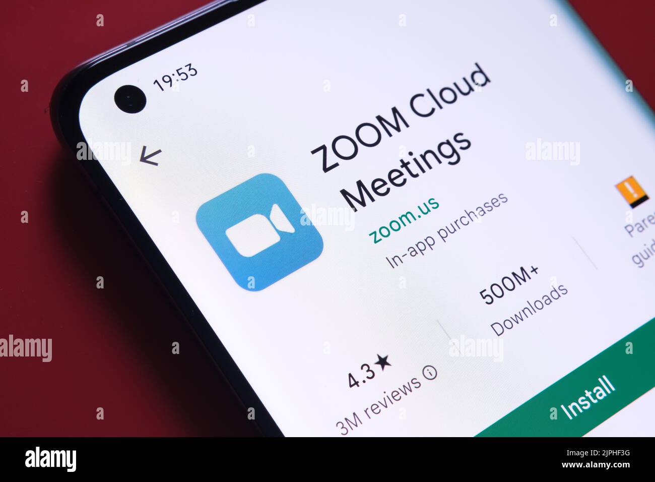 Application Zoom sur le Cloud meetings affichée dans Google Play Store sur l'écran du smartphone placé sur un arrière-plan rouge. Gros plan avec mise au point sélective. Stafford, ONU Banque D'Images