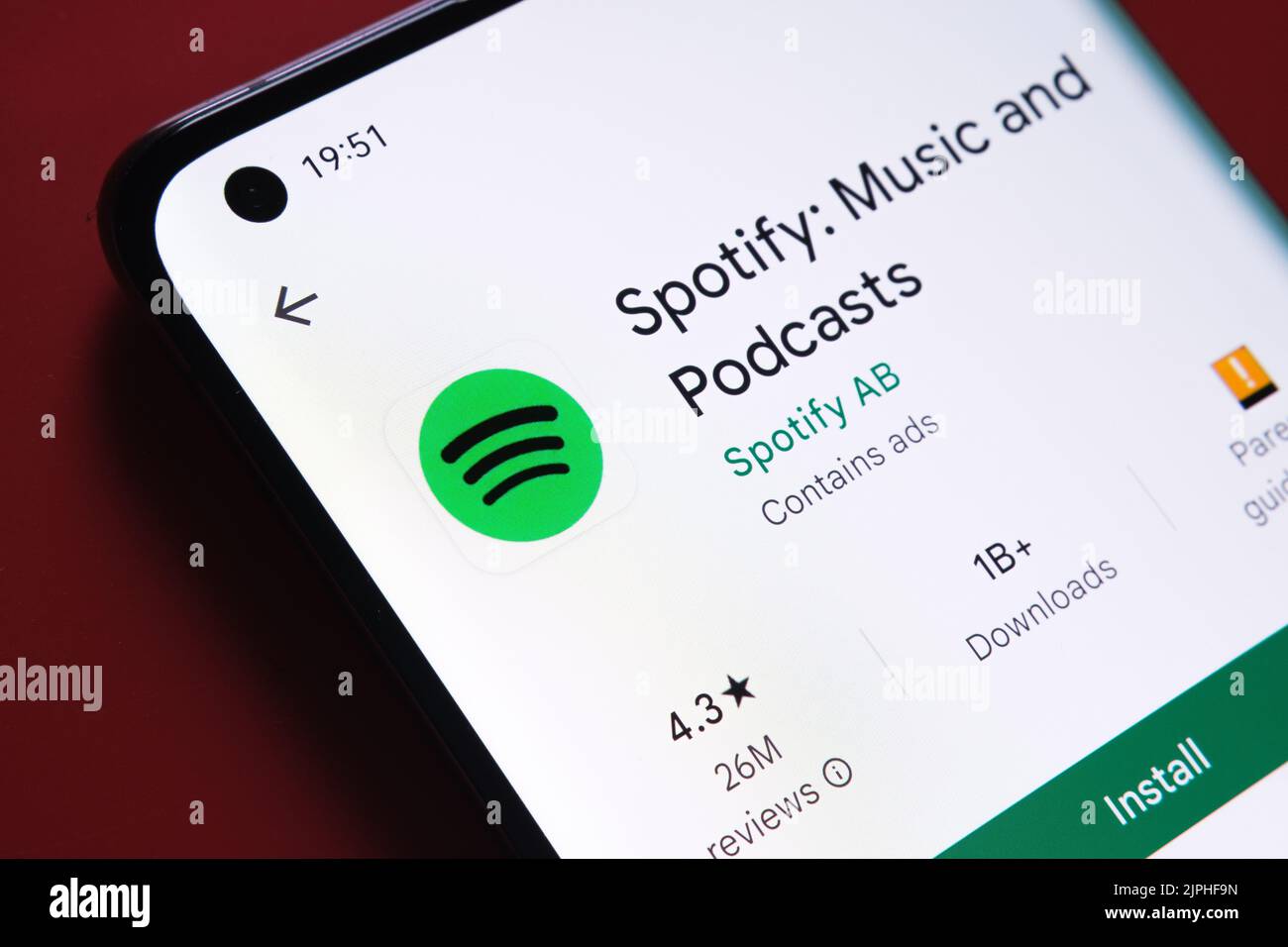 Application spotify visible dans Google Play Store sur l'écran du smartphone placé sur fond rouge. Gros plan avec mise au point sélective. Stafford, Royaume-Uni Banque D'Images