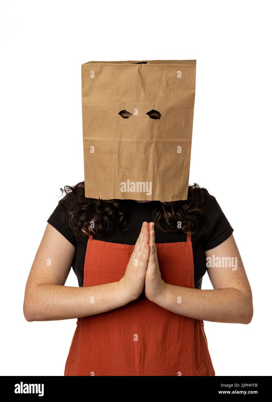 Femme portant un sac en papier sur sa tête et tenant ses mains pour prier. Banque D'Images