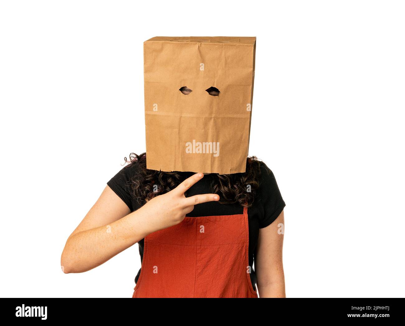 Jeune femme portant un sac en papier sur sa tête tenant la main comme des ciseaux Banque D'Images