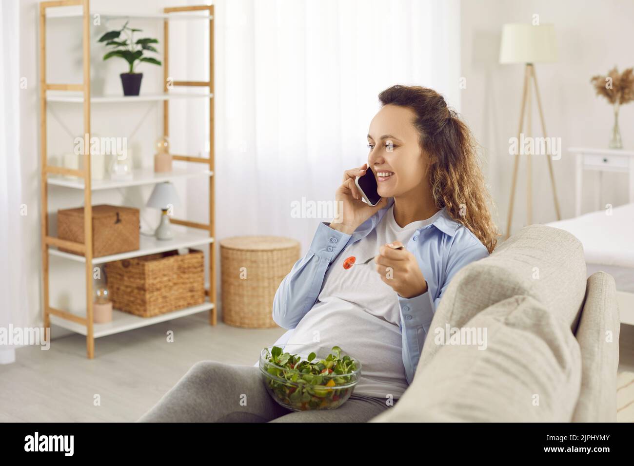 Femme enceinte souriante manger une salade saine parler sur la cellule Banque D'Images