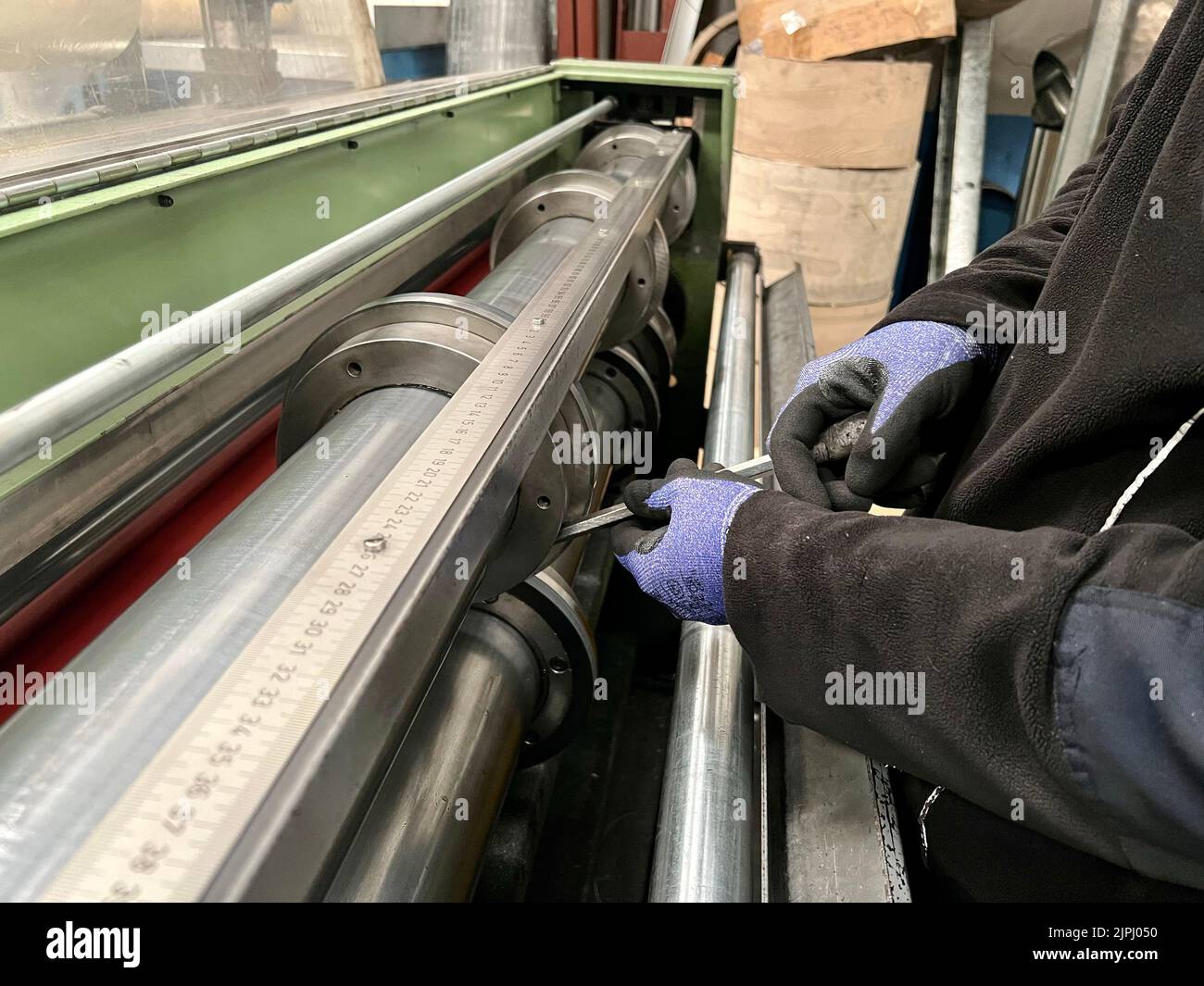 Un homme qui a placé les lames d'une machine de découpe de tôle dans une usine Banque D'Images