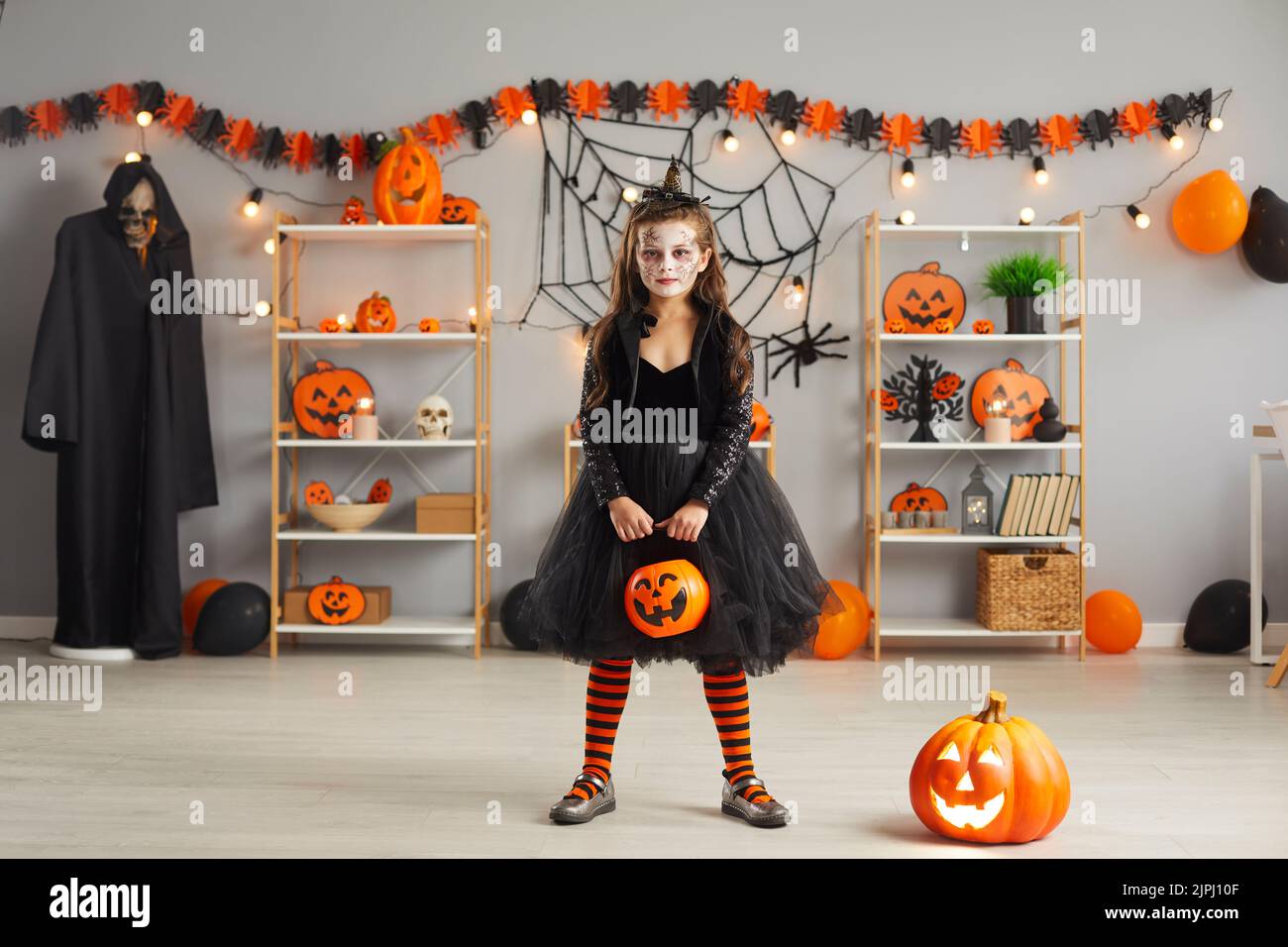 Portrait d'une fille vêtue d'un costume de sorcière sinistre tenant un seau de citrouille d'Halloween Banque D'Images