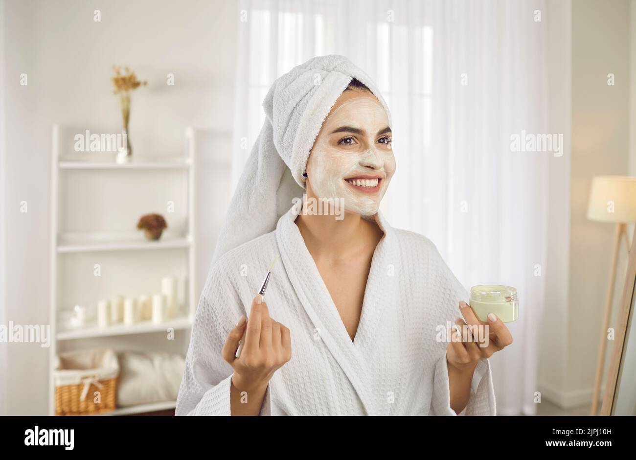 Portrait de la belle jeune femme appliquant un masque cosmétique pendant la routine de beauté du matin. Banque D'Images