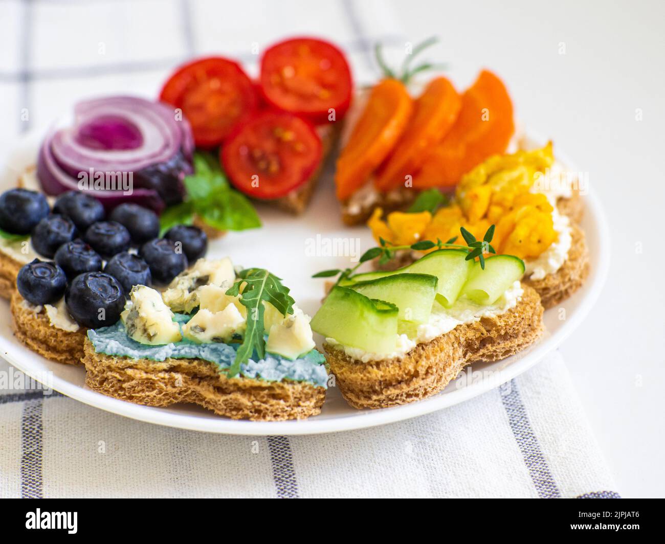 Sandwichs arc-en-ciel en forme de coeur sur table blanche Banque D'Images